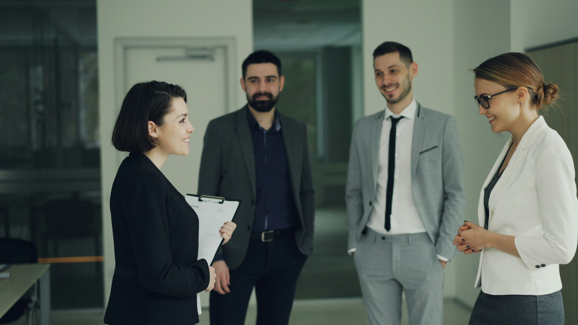 Four professionals in suits discussing in an office.